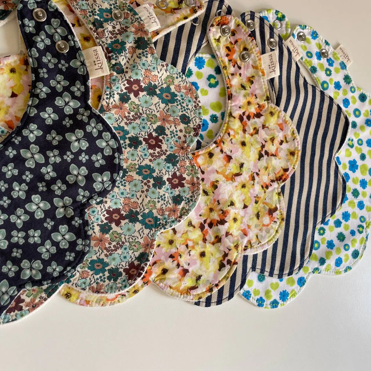 A pile of flower bibs in navy, florals and stripes