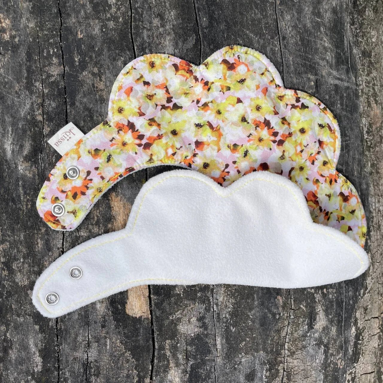 A meadow print bib lying over a cream microfleece back