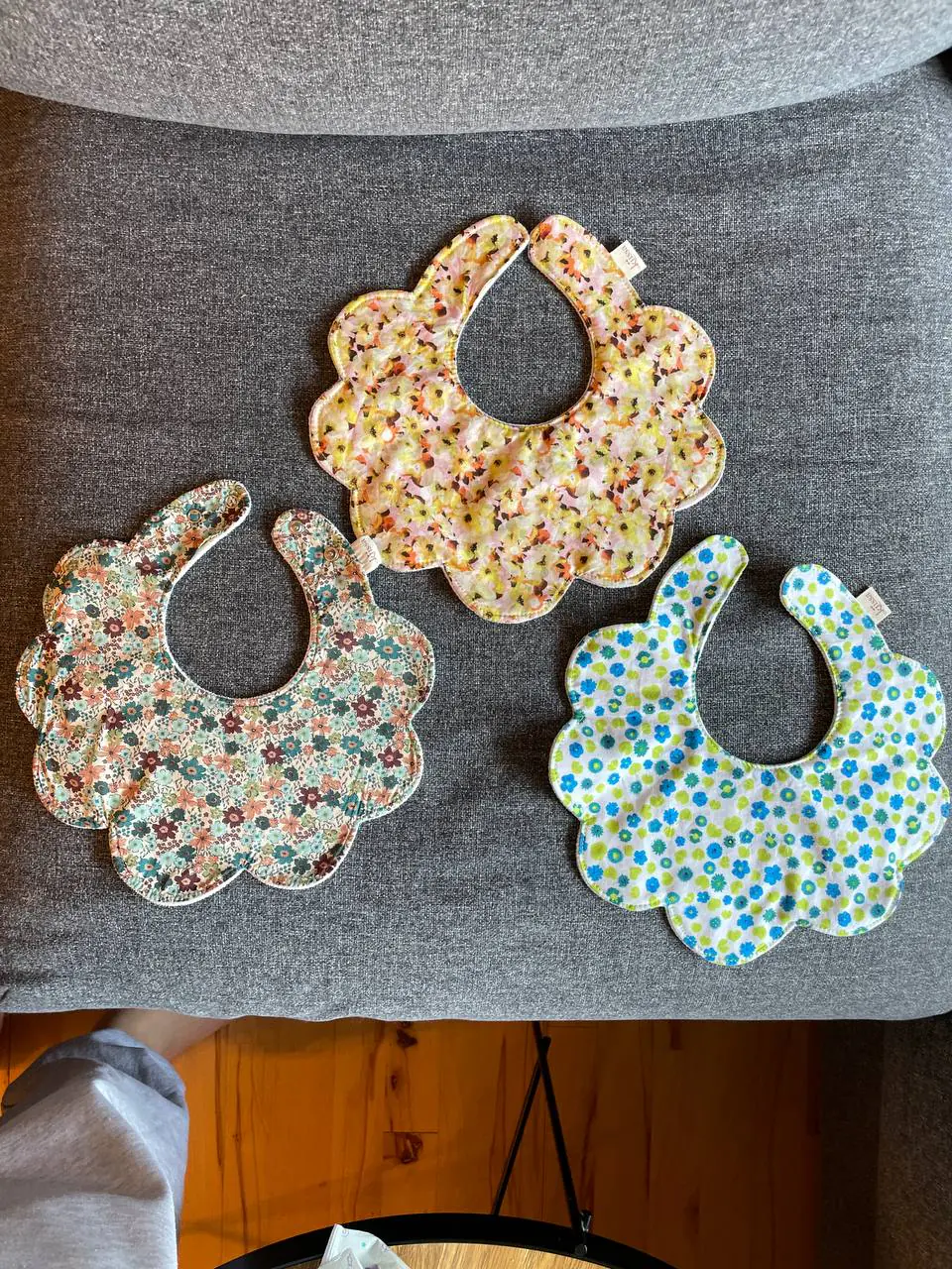Three flower bibs side by side on the sofa
