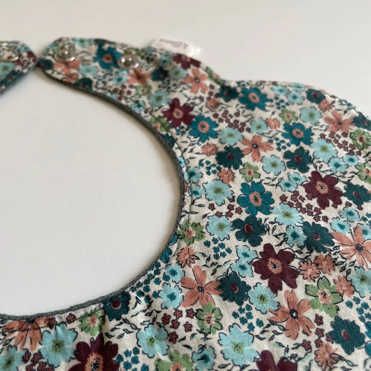 Hand-finished edges of a floral bib in soft daylight