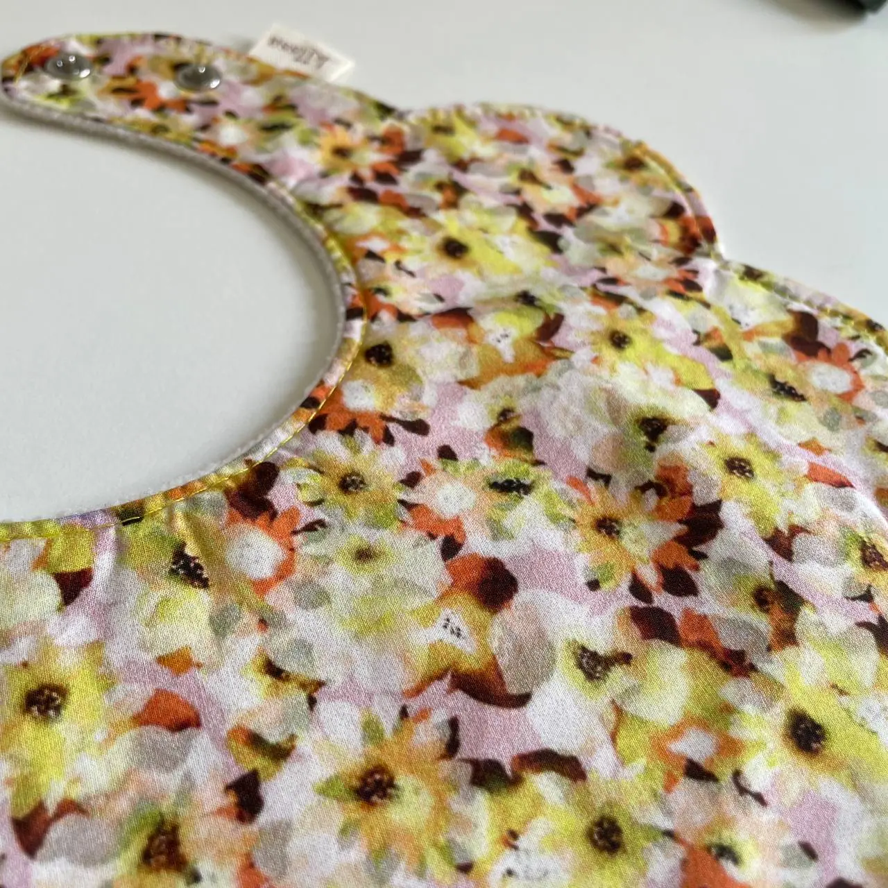 The texture of a yellow floral cotton bib, photographed up close