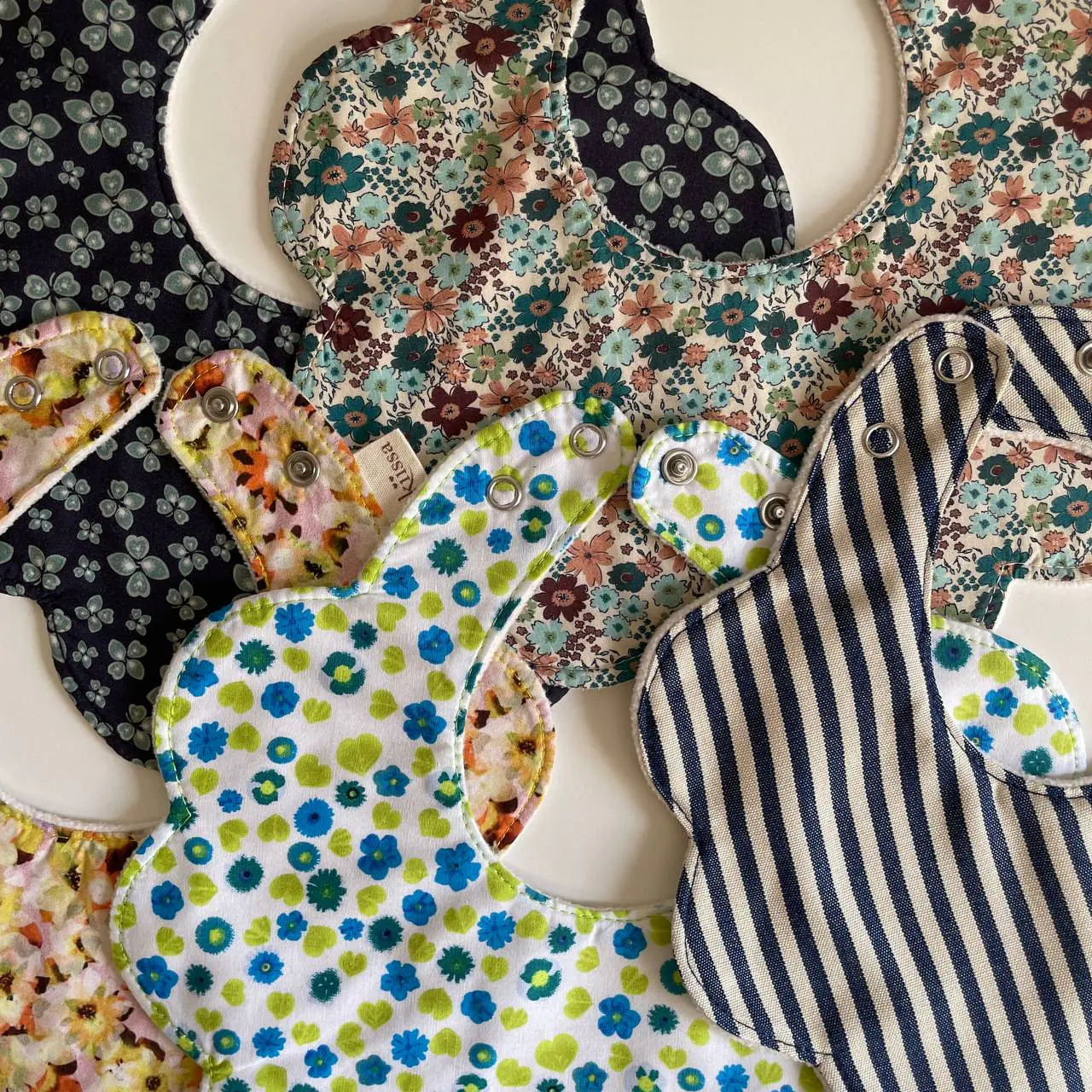 Layers of handmade bibs showing fabrics and stitching